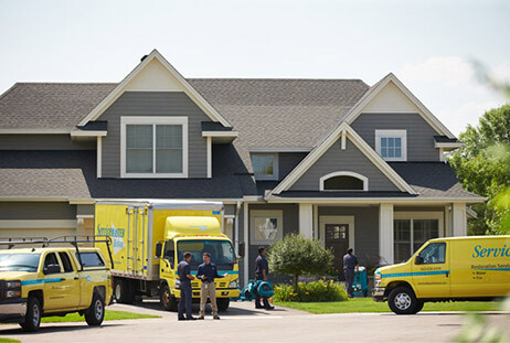 Three ServiceMaster Restore vehicles and crew in front of a customer's home