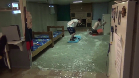 Guys playing on sleds in flooded basement