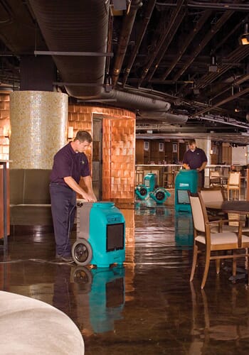 Two ServiceMaster technicians employing flooding equipment during large loss recovery services in a Redding restaurant