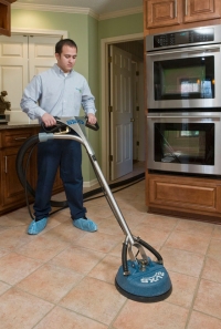 Man cleaning kitchen tiles with equipment