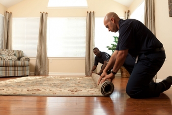 Two men rolling up a rug