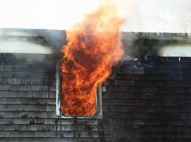 flames coming out of upstairs window in a house on fire