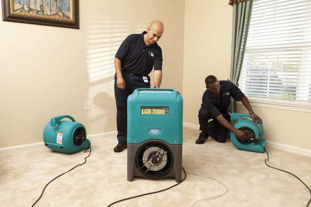 Two ServiceMaster technicians preparing a living room for carpet cleaning services in San Angelo, TX