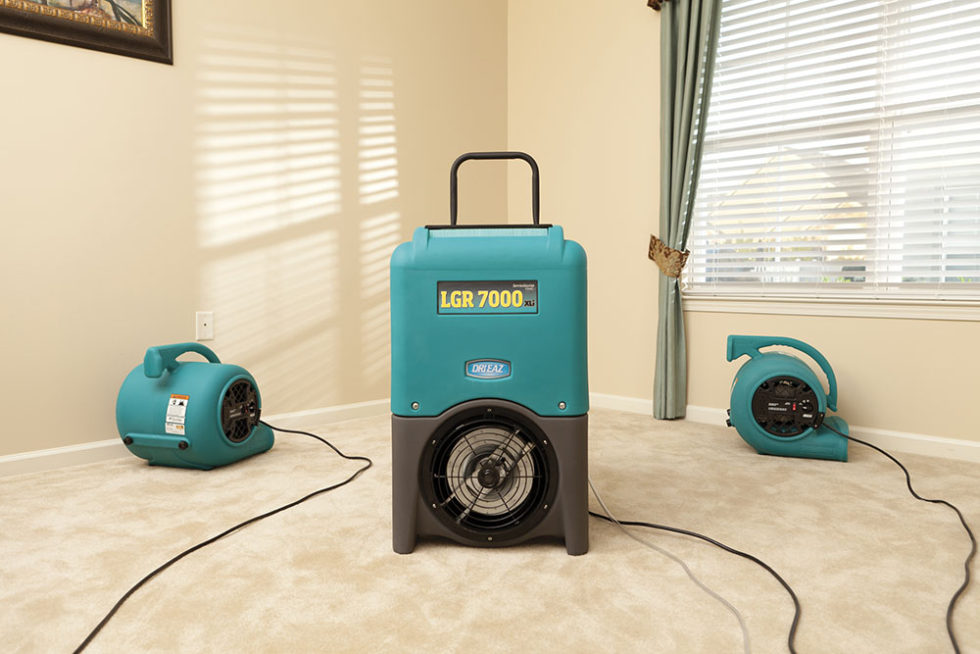 water damage restoration team using large fans to dry out carpet