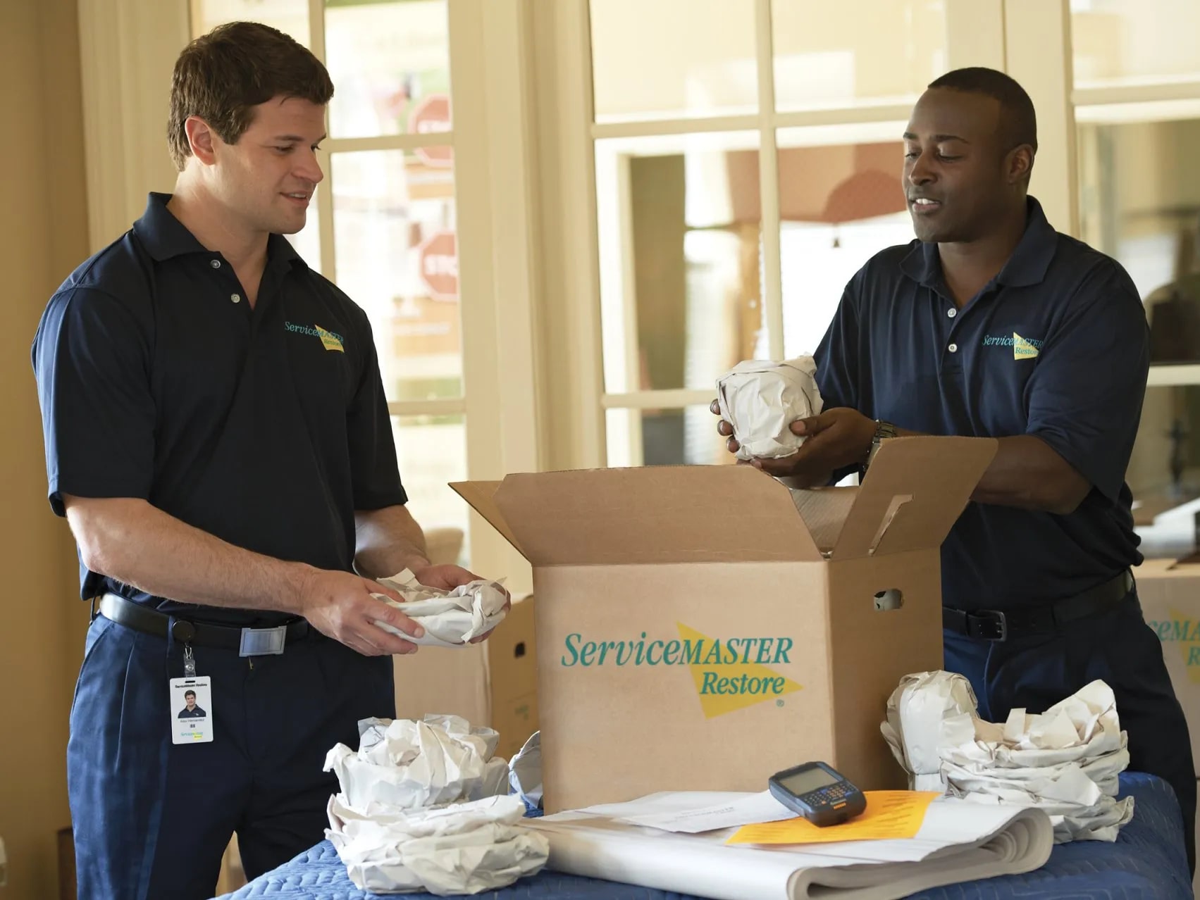 Two ServiceMaster technicians preparing and packing belongings during content restoration in Fresno, CA