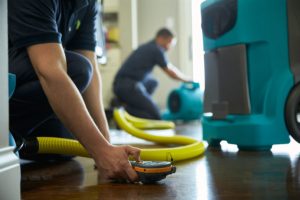 Two ServiceMaster technicians in Feasterville, PA using water damage equipment in a home