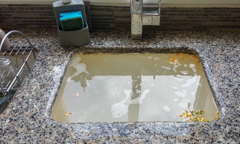 A kitchen sink backed up with sewer water before water damage restoration services in Lafayette