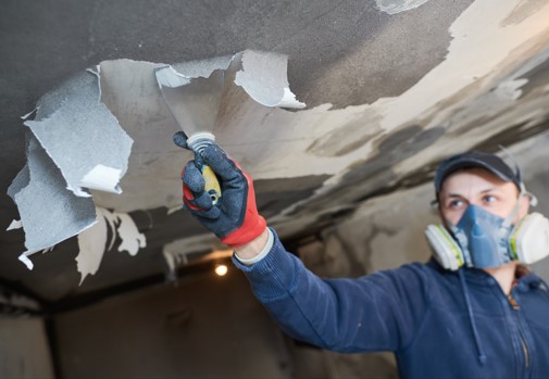 man scraping smoke damage off of ceiling