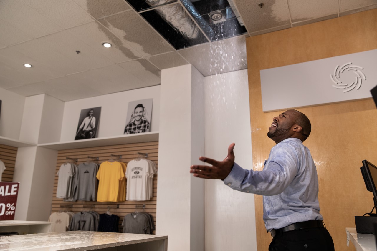 A business owner looks up incredulously at his clothing store’s leaking and broken ceiling after storm damage in Neillsville, Wisconsin