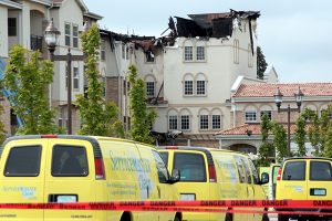 Commercial  building destroyed and yellow trucks driving towards it