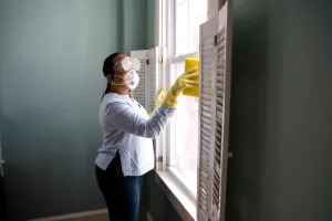 Person with safety equipment cleaning near a window