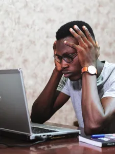 Man Holding his Head While Looking at Laptop