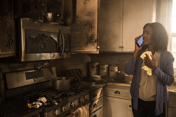 Woamn standing in kitchen on the phone after kitchen fire