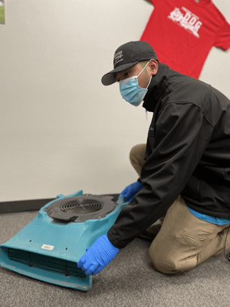 ServiceMaster employee with drying machine providing Visalia water damage restoration