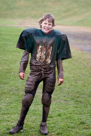 A boy in a muddy football uniform