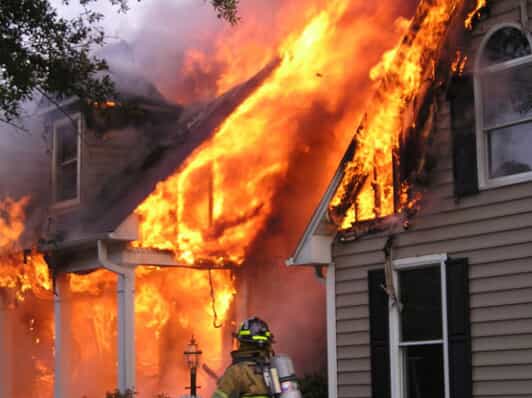 A home on fire and firefighter in front