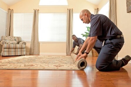 Two men rolling out a rug