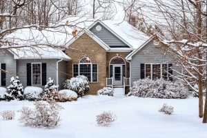house with snow on roof on snow covered ground 