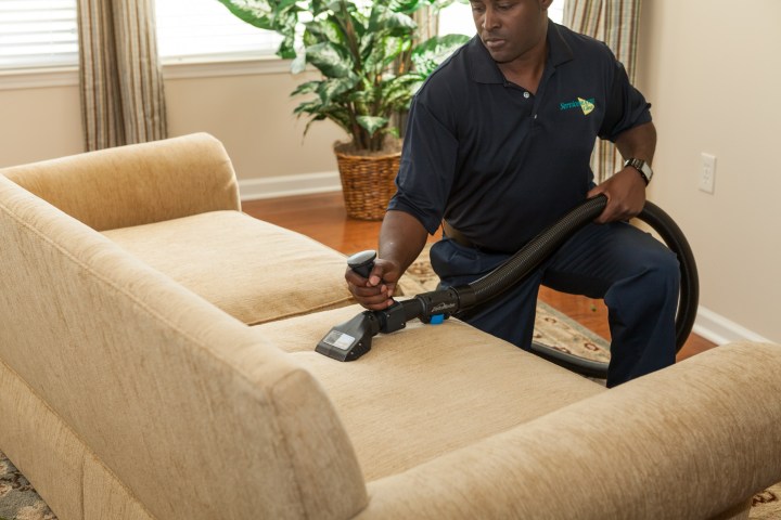 man vacuuming a couch