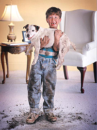 Boy holding messy dog over clean carpet