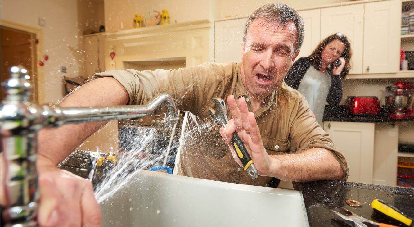 Man Trying to Fix Busted Kitchen Pipe