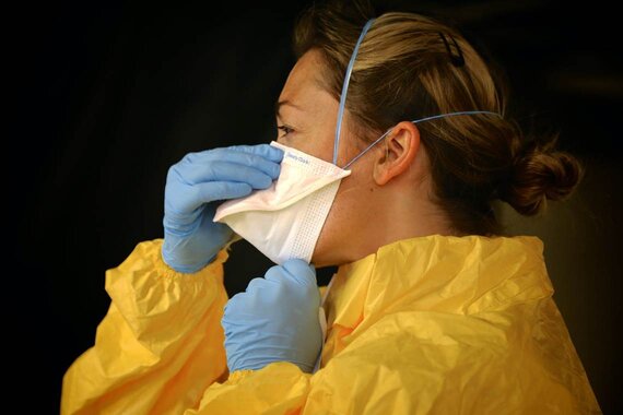 Woman Wearing Gloves, Body Protectant, and Adjusting Face Mask