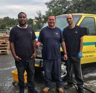 Three men standing in front of a van smiling