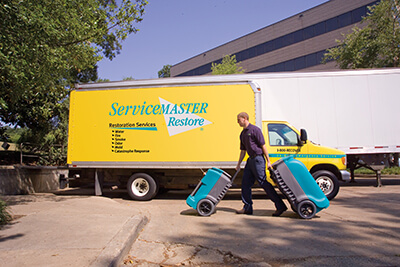 Servicemaster truck and a worker bringing working materials