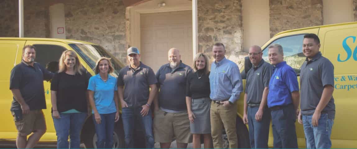 Staff photo of smiling people infront of a home