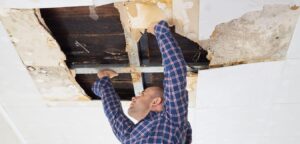 A man removing ceiling board that has been damage by a leak