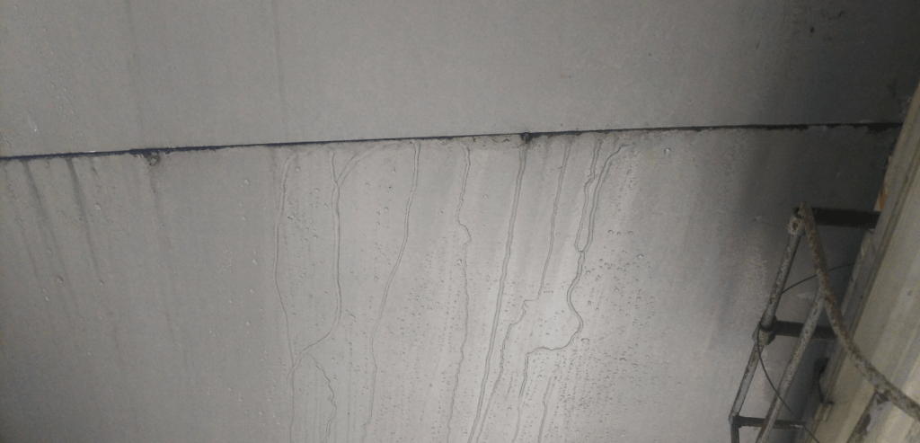 Water runs along the wall of a commercial facility