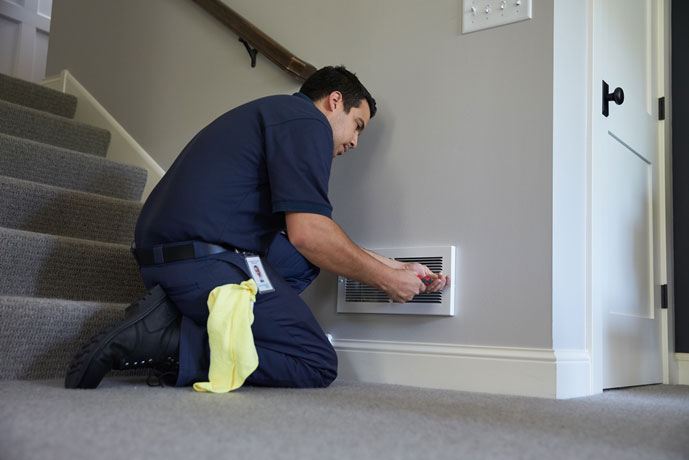 A ServiceMaster technician replacing a vent in a home after mold restoration was completed