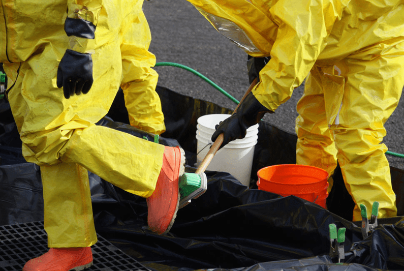 Two technicians in biohazard suits following biohazard cleanup best practices