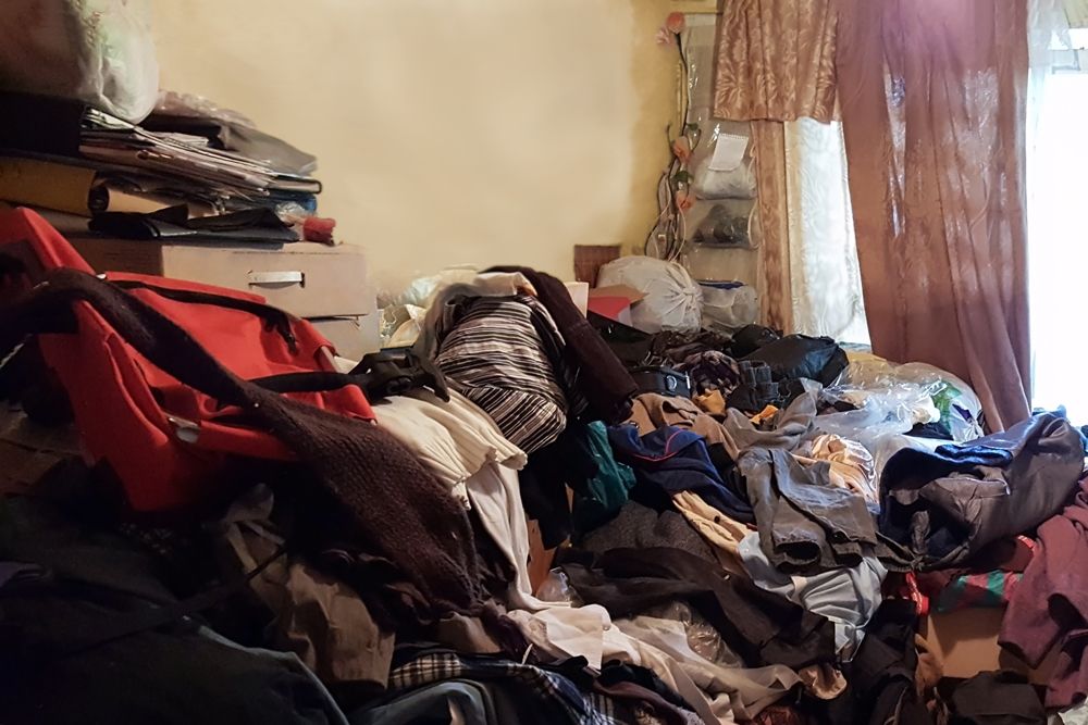 A large pile of clothes, documents and other items filling up the bedroom of a home