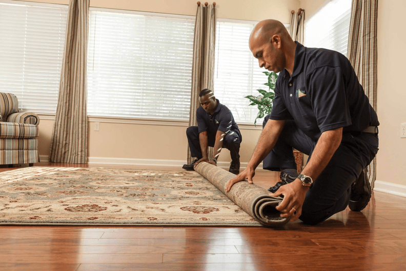 Two men rolling up a carpet